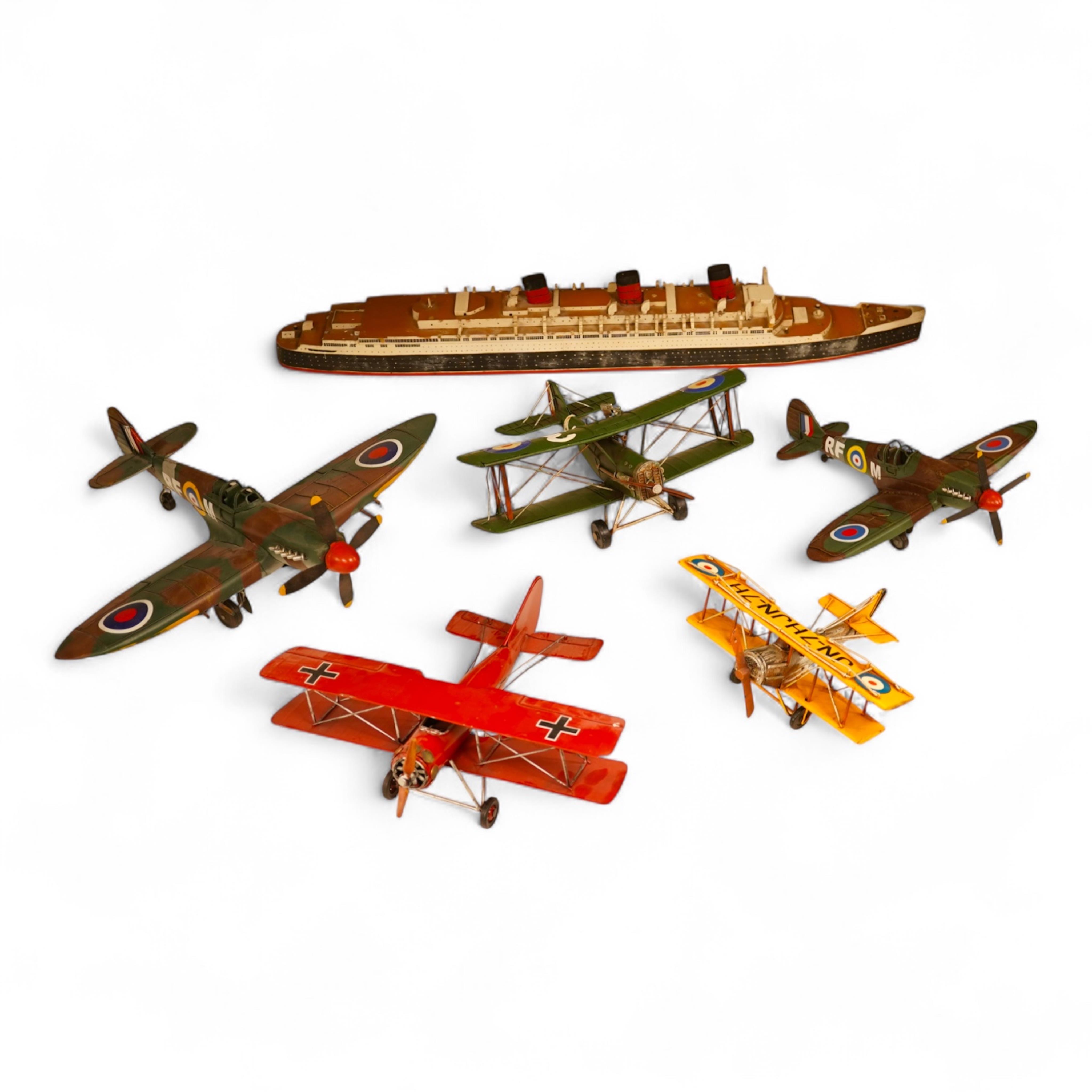 Five decorative metal models of military aircraft, including two Supermarine Spitfires, two First World War, British bi-planes, a German Albatros D.III bi-plane, and a wooden model of RMS Queen Mary, hull 77cm long